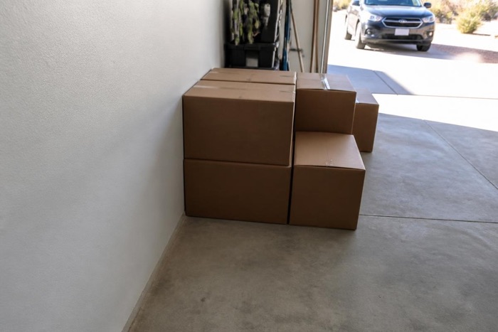 Cardboard boxes stacked against a garage wall where it meets the slab