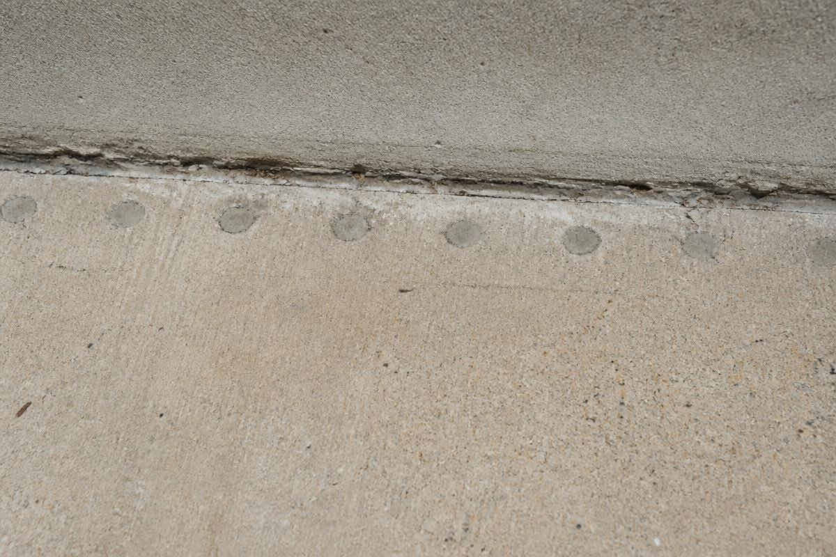 Line of plugged drill holes along a concrete slab edge from a previous termite treatment